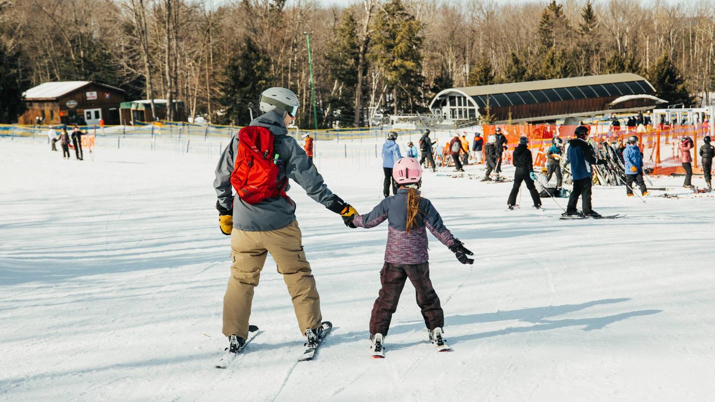 A father and daughter skiing down towards the Comet lift.