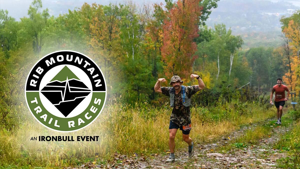 Trail runner flexes triumphantly amidst colorful autumn foliage.