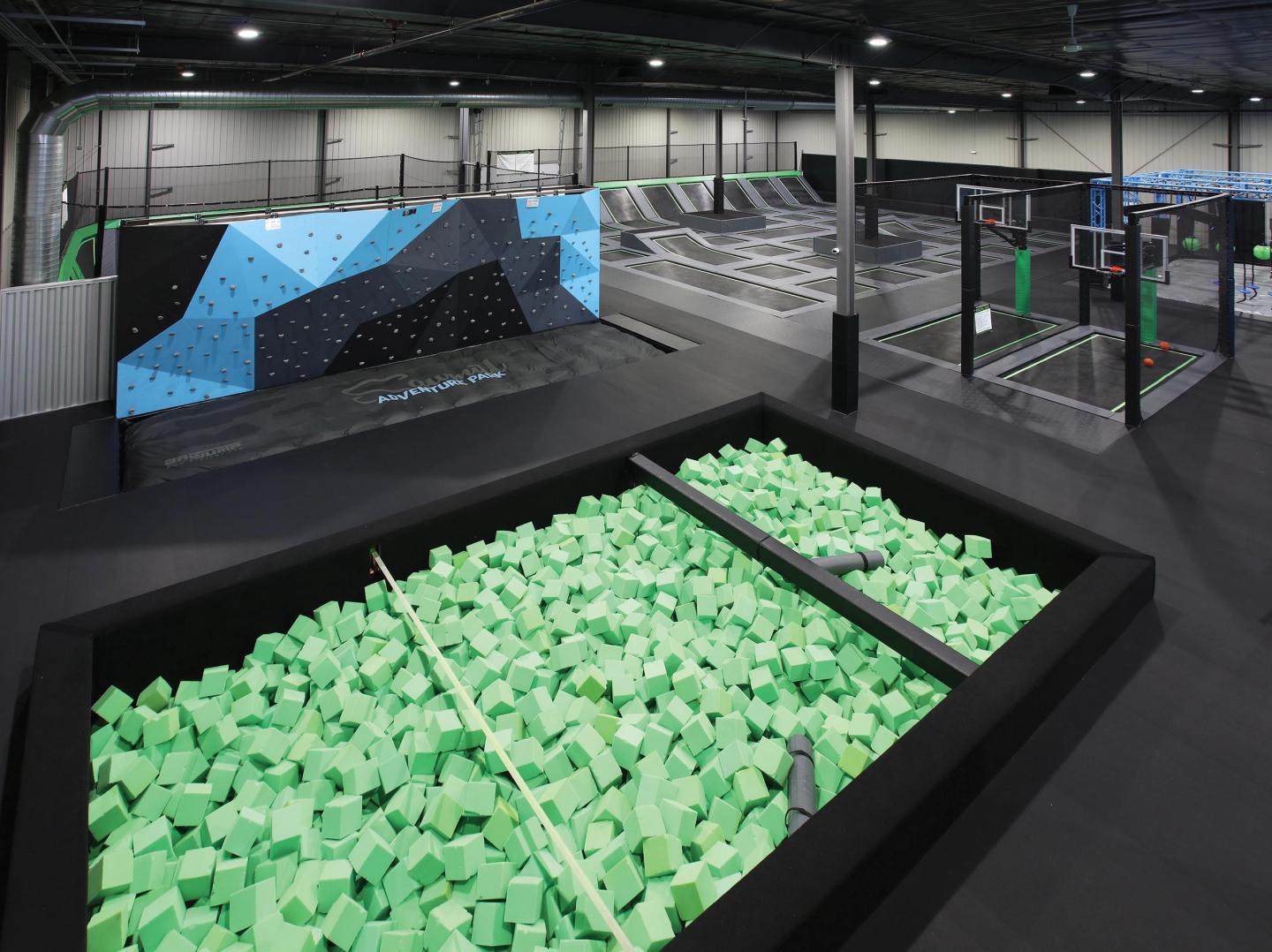 Indoor trampoline park with foam pit, climbing wall, and trampolines.