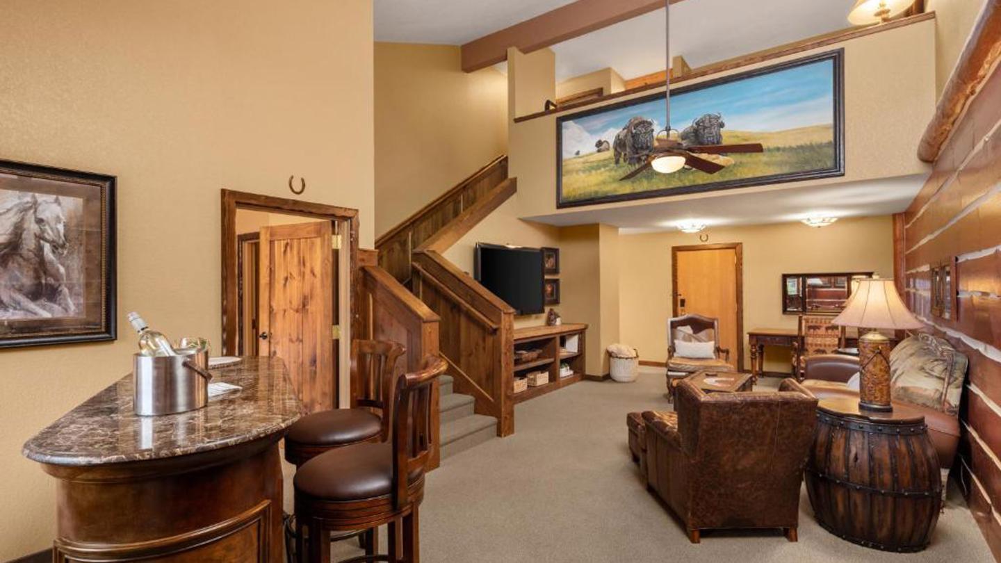 Cozy lodge interior with rustic décor, bar, and loft area.