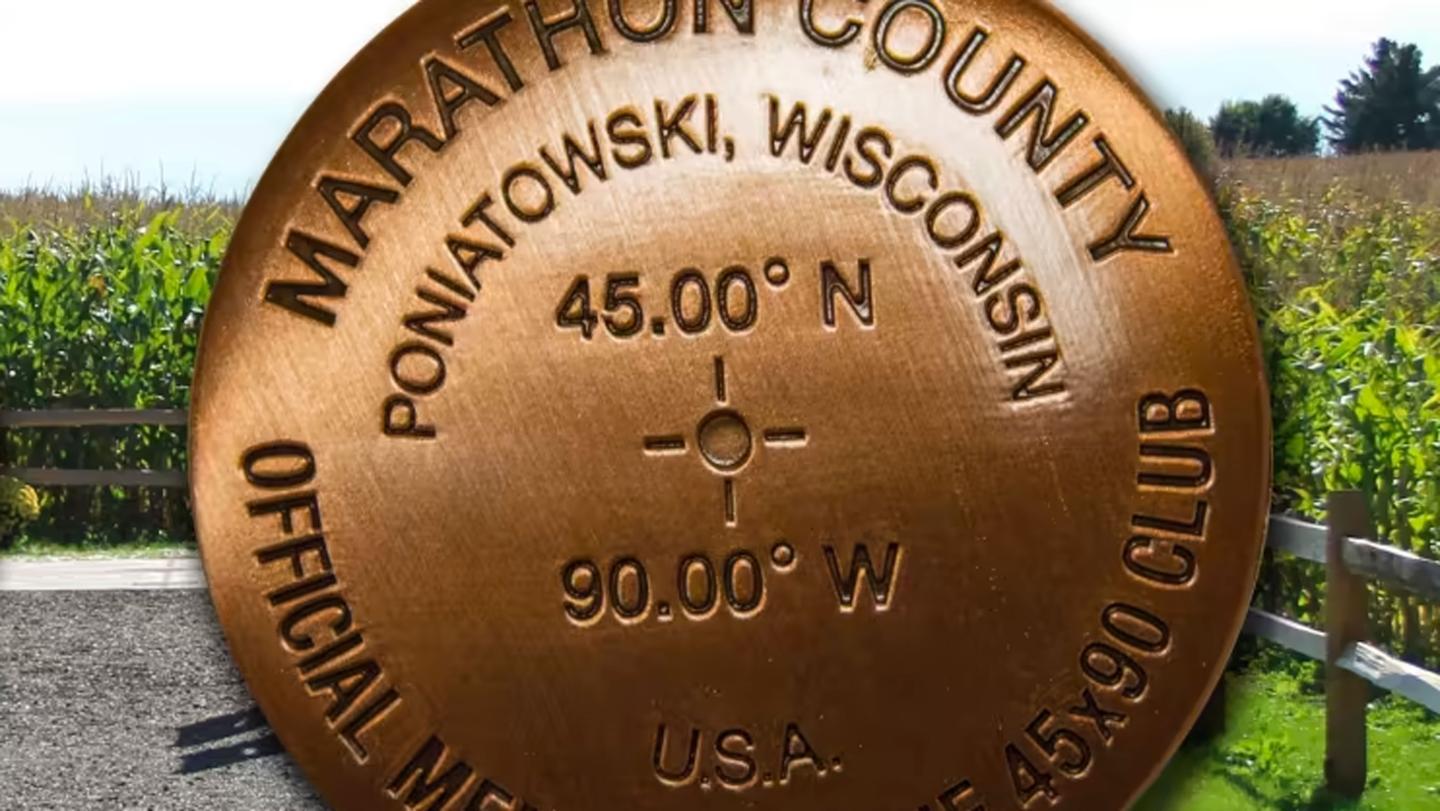 Bronze medallion with coordinates, field in background.