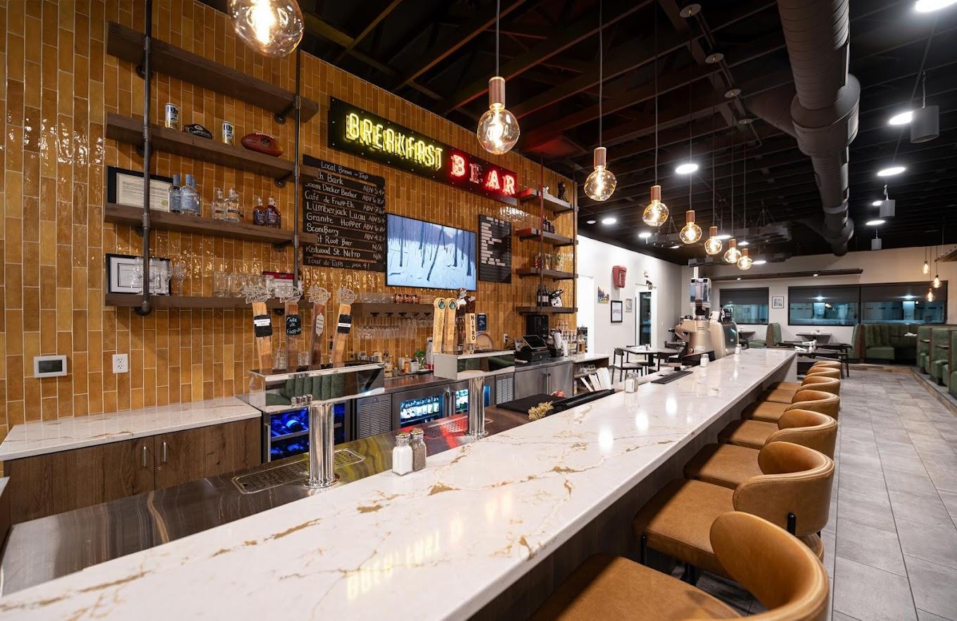 Trendy bar with a long marble counter, warm lighting, and rows of bar stools.