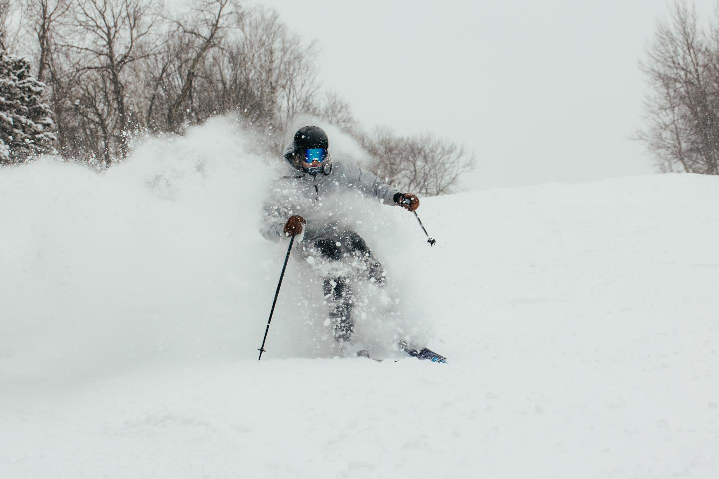 Skier in blue goggles navigating through snow on a snowy slope.