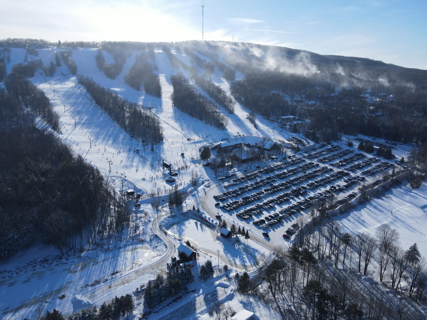 Snow-covered ski resort with slopes, buildings, and clear blue sky.