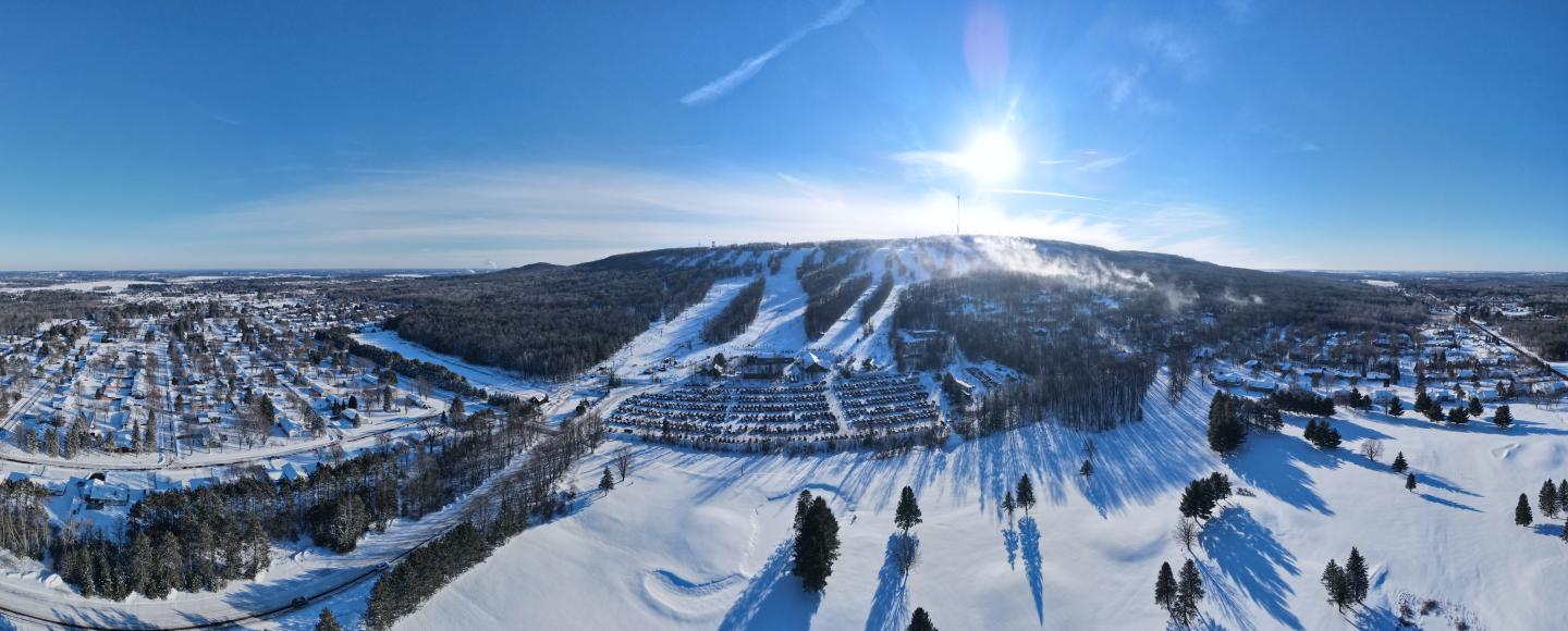 Snowy mountain landscape under clear blue sky with bright sun.