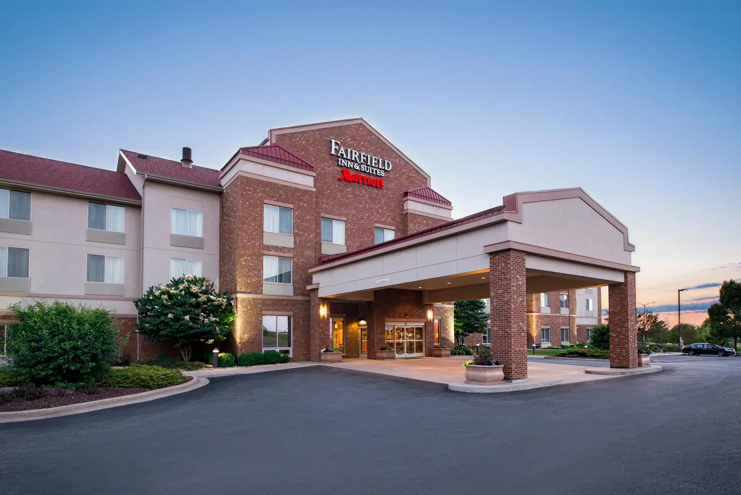 Hotel exterior with red accents at dusk, clear sky in the background.