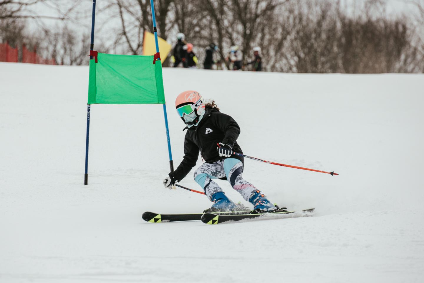 Person skiing downhill on a snowy slope, wearing a helmet and goggles.