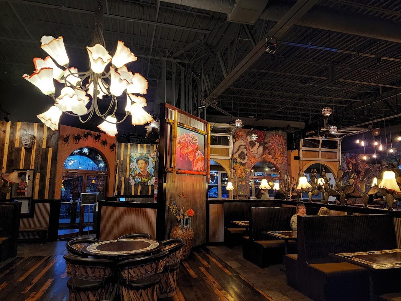 Dimly lit restaurant with colorful art, booths, and decorative lighting.