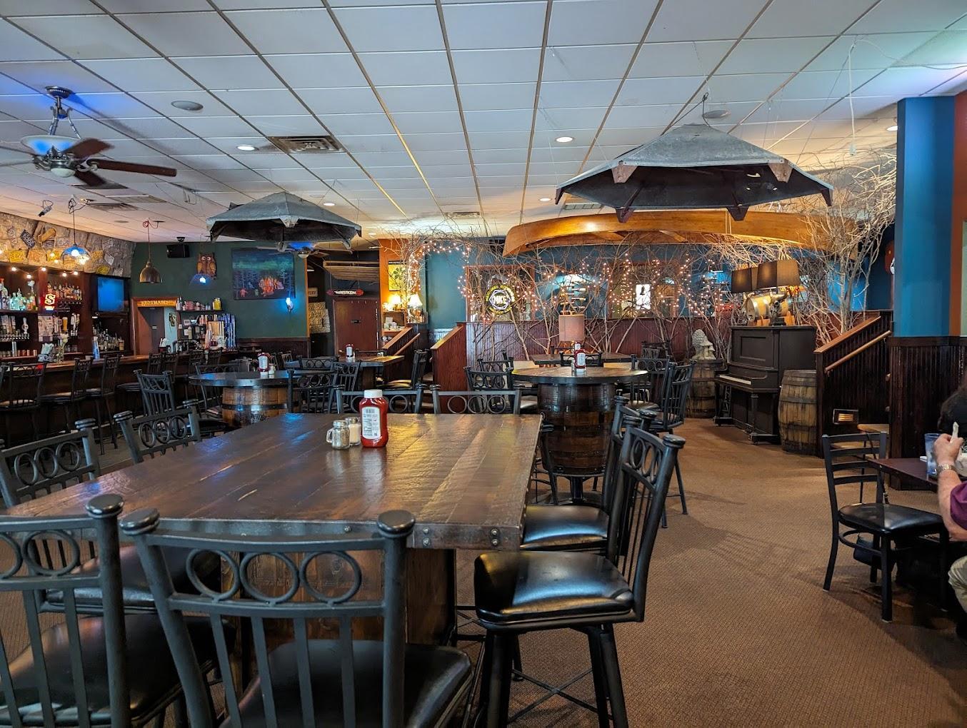 Cozy restaurant interior with wooden tables and chairs, dim lighting, and painted murals.