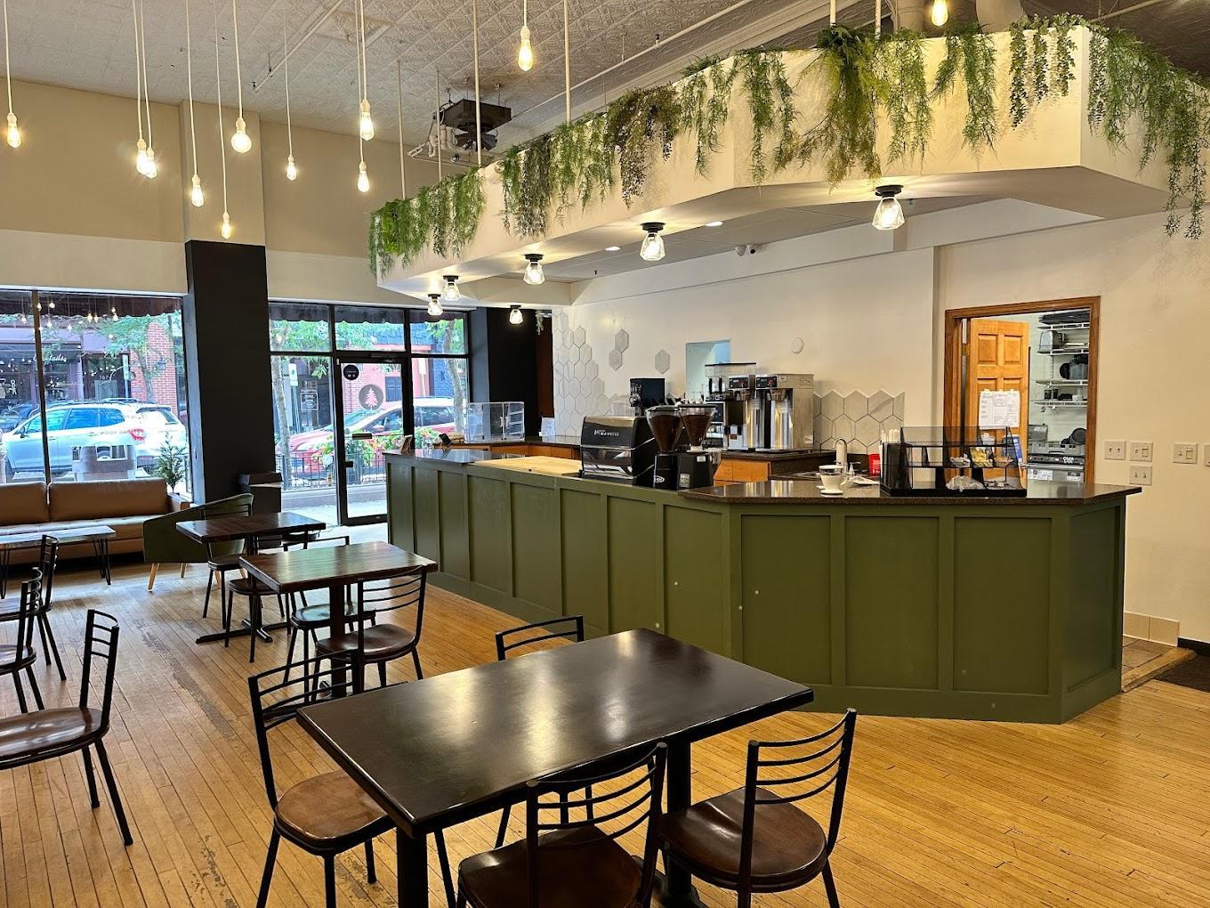 Cozy café interior with green counter, tables, and hanging lights.