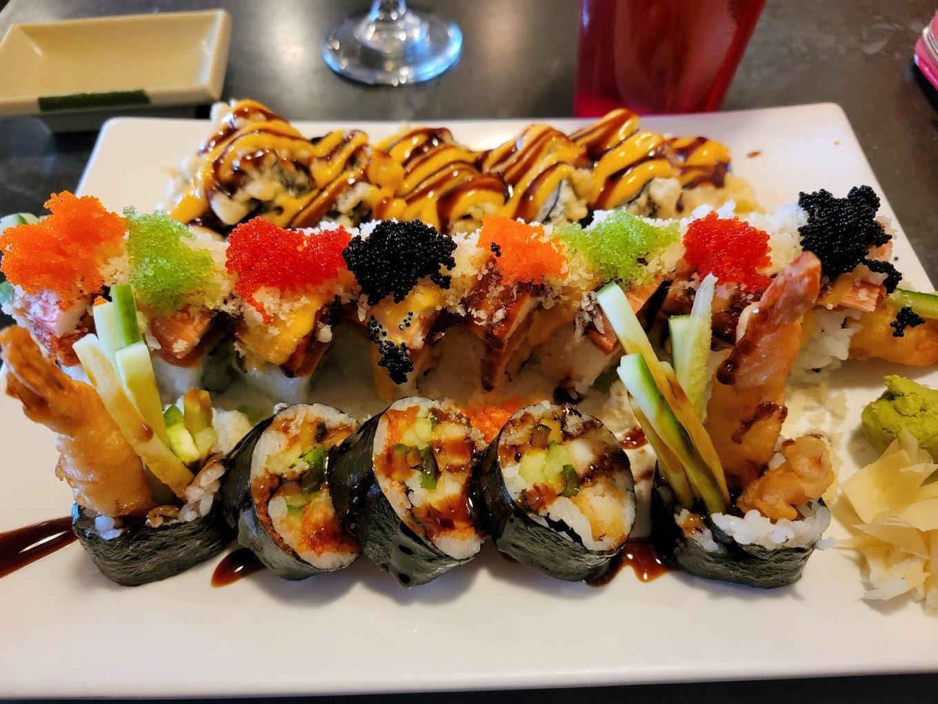Assorted sushi rolls with vibrant toppings on a white plate.