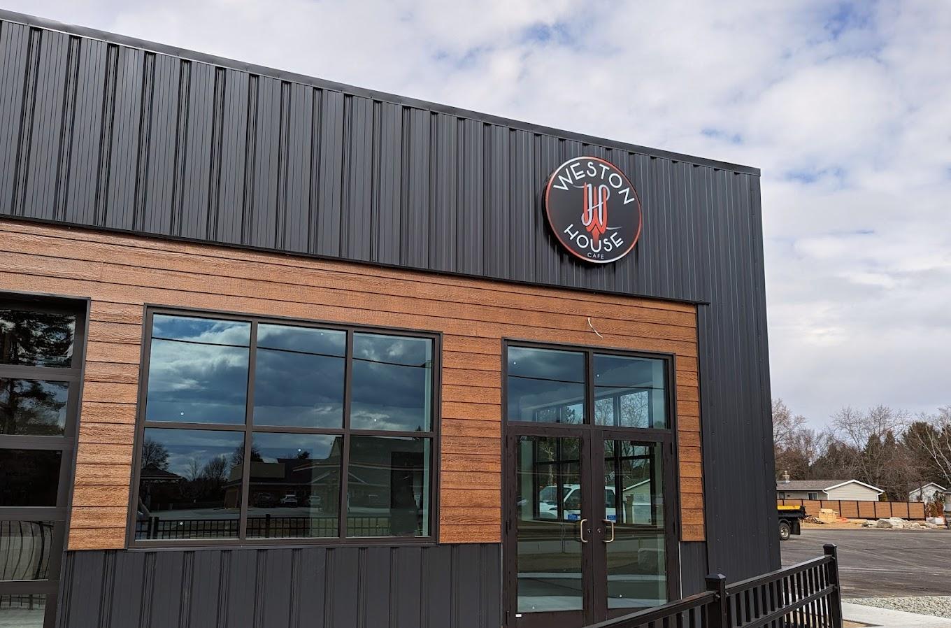 Modern building with wood paneling and large windows under a cloudy sky.