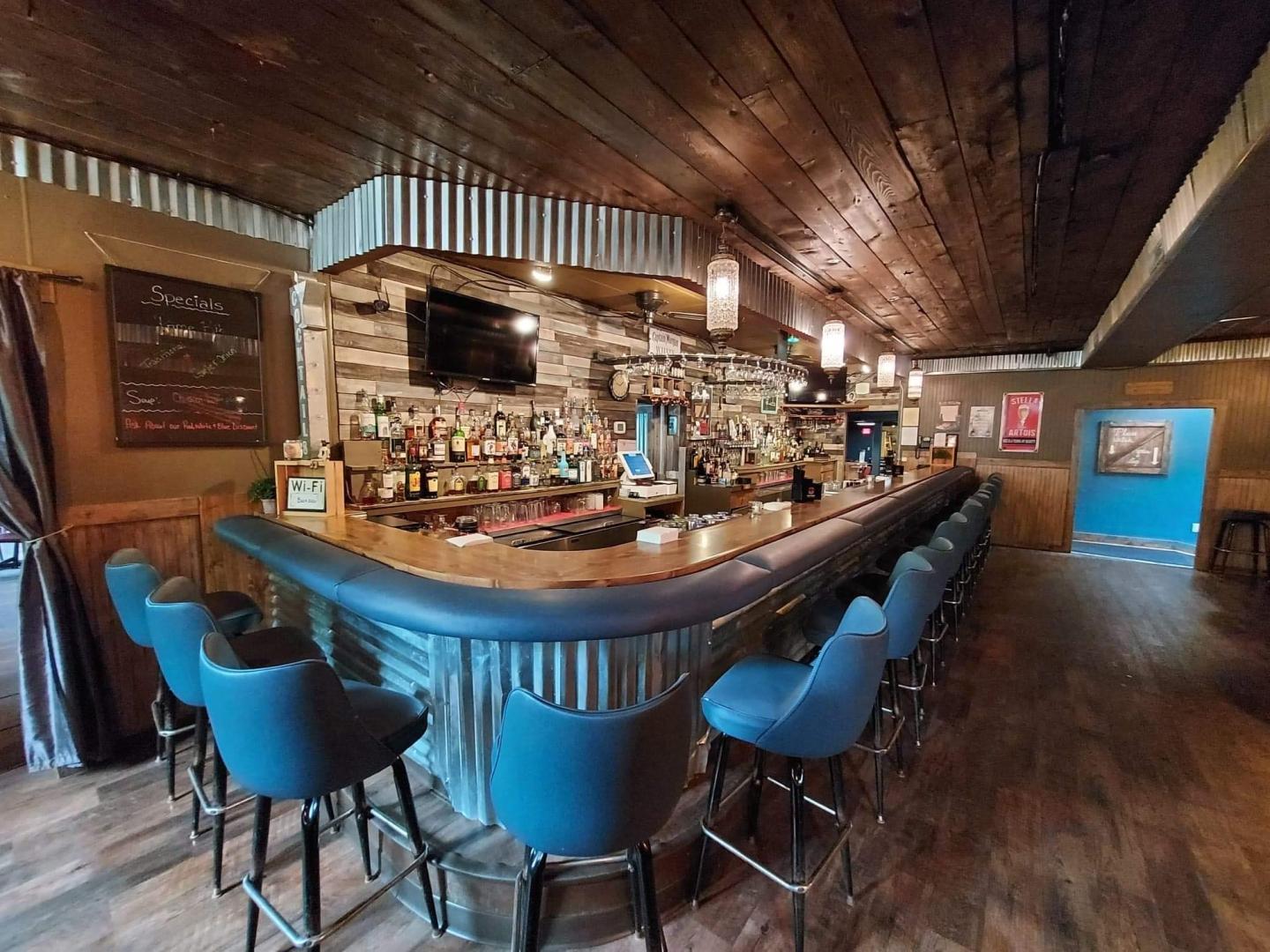 Dimly lit bar with blue stools and wooden decor.