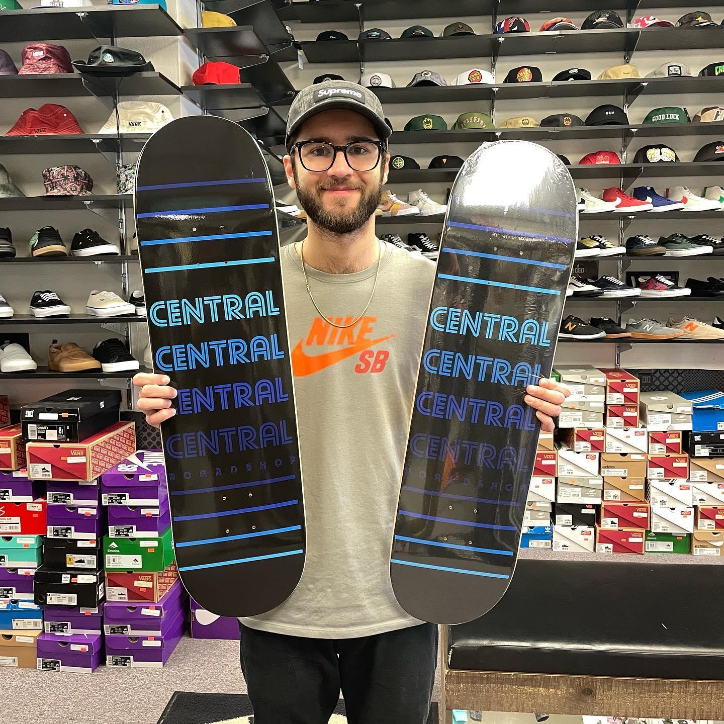 Man holding two skateboards in a shoe store, smiling.