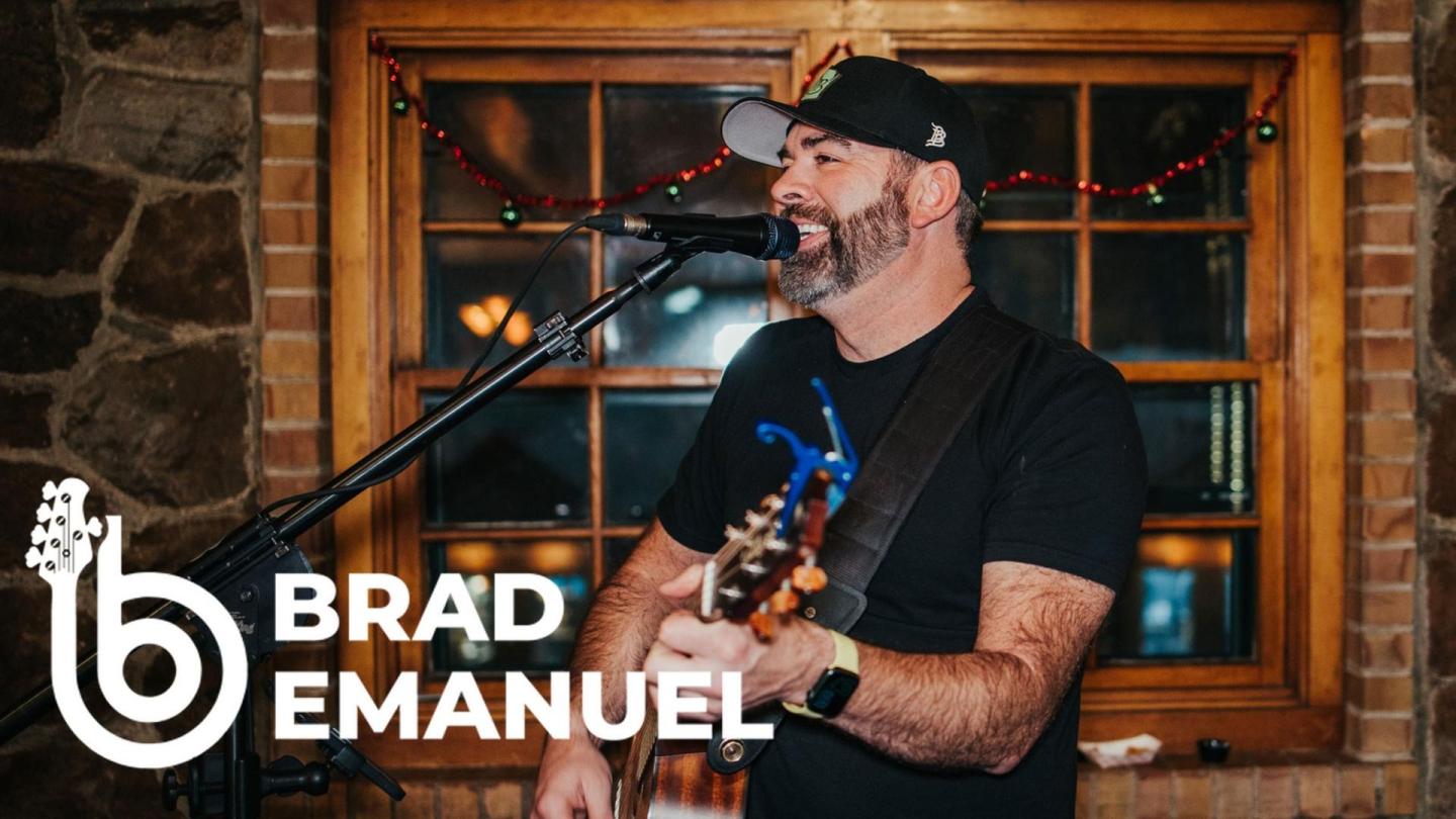 Musician singing and playing guitar in cozy, warmly lit room.