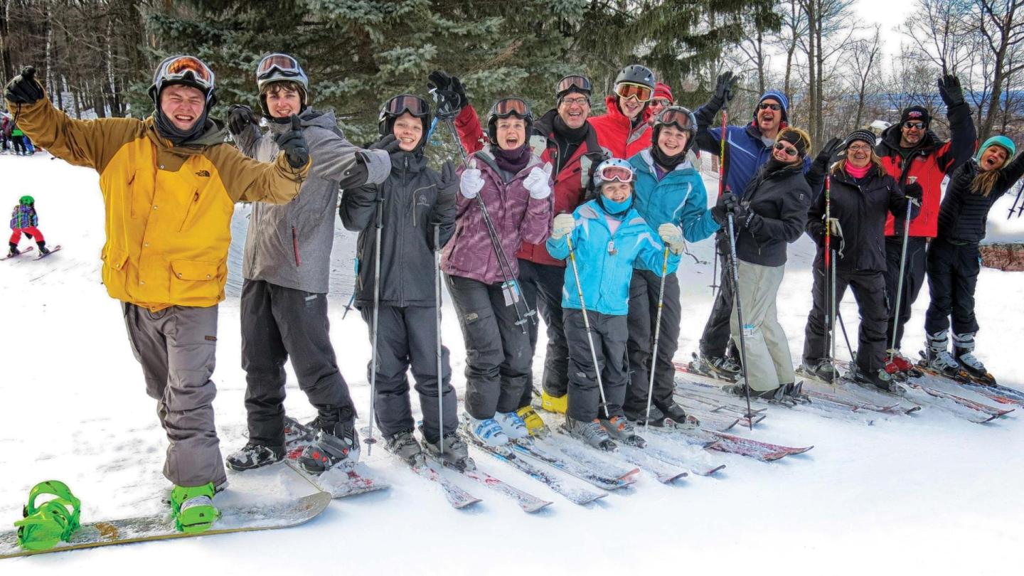 Group of skiers in colorful jackets smiling on a snowy slope.