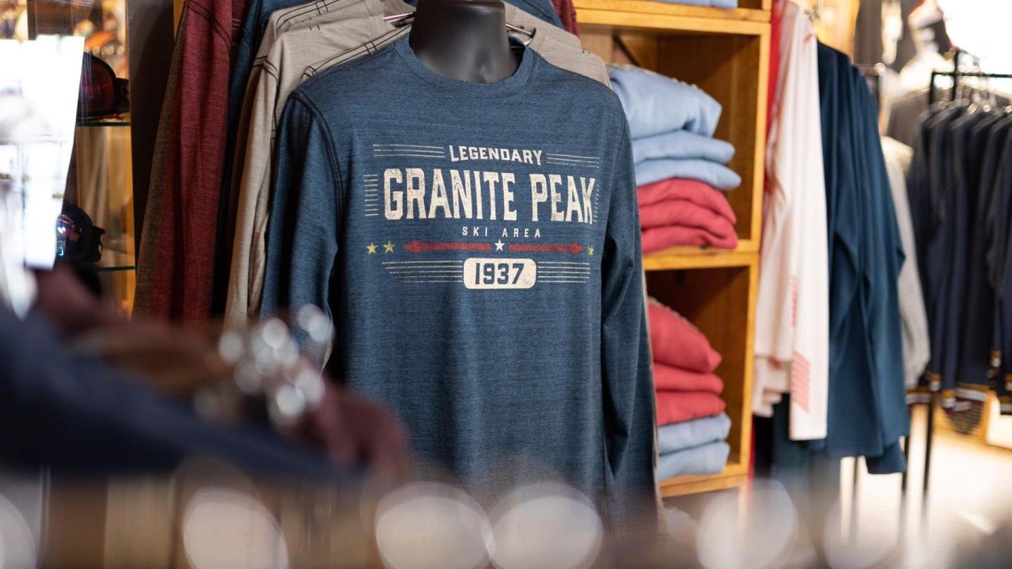 Mannequin wearing "Granite Peak" sweatshirt, surrounded by folded sweaters.