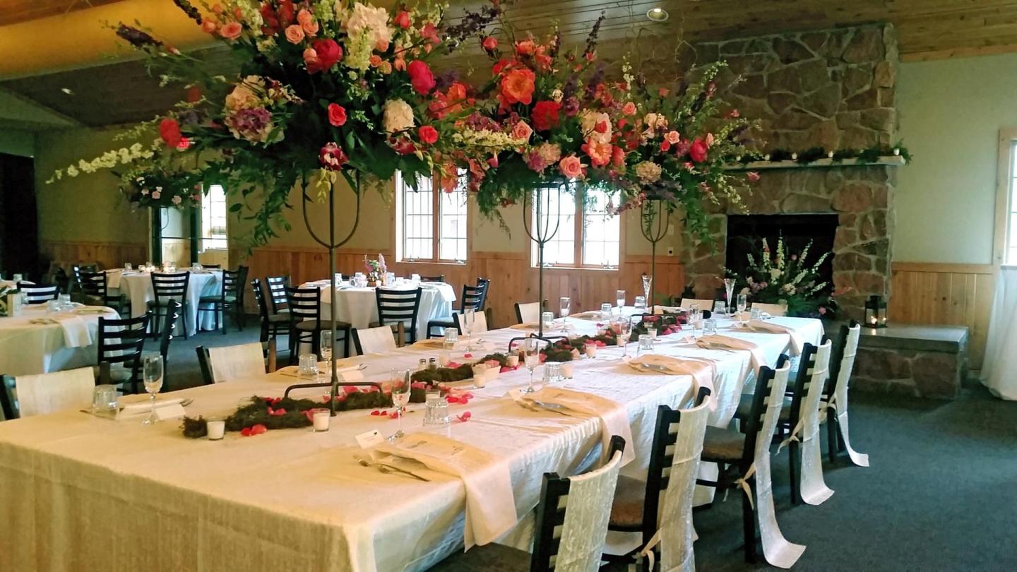 Elegant dining room set for an event with floral centerpieces and white tablecloths.