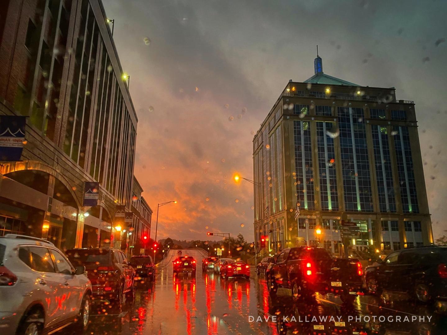 City street at sunset, wet pavement reflecting car lights.