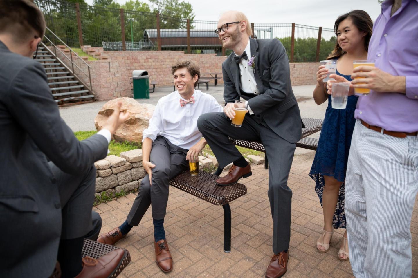 Group of people in formal attire chatting and holding drinks outdoors.