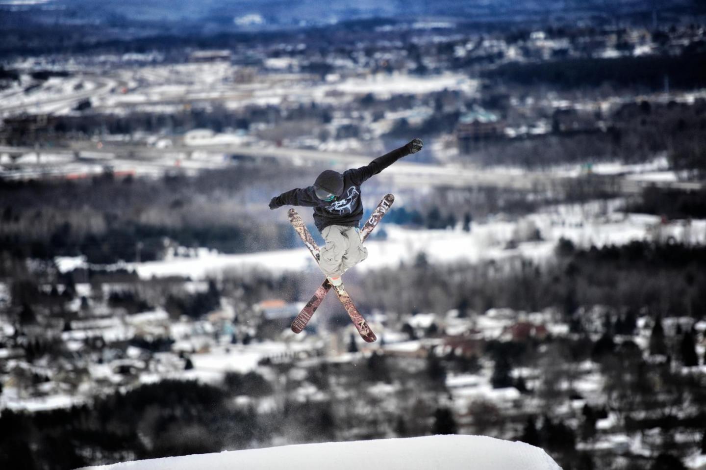 Snowboarder airborne over snowy landscape, performing a trick.