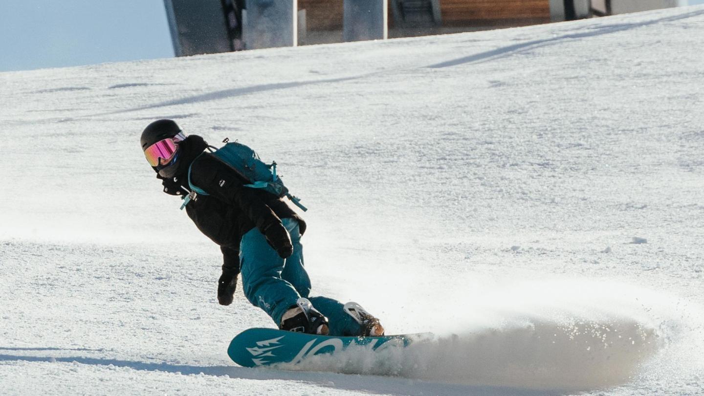 Snowboarder in blue gear descending a snowy slope.