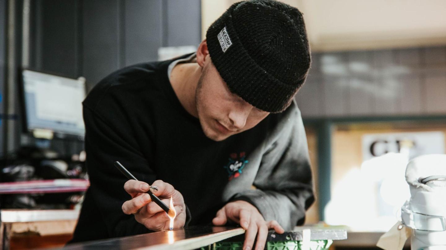Person in black beanie focused on detailed work indoors.