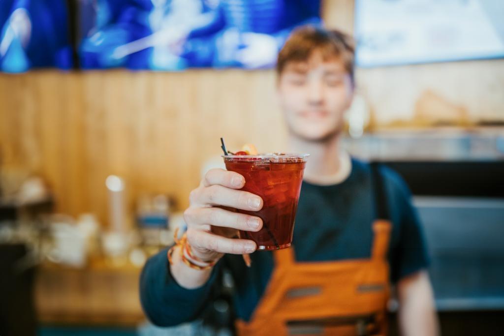 Bartender holding a cocktail glass forward, smiling.