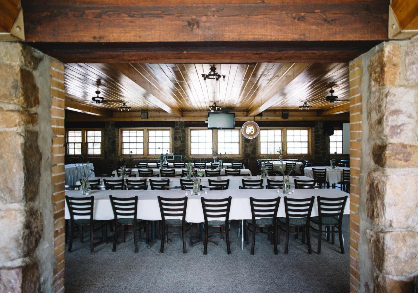 Long dining tables set up in a rustic, wooden banquet hall.