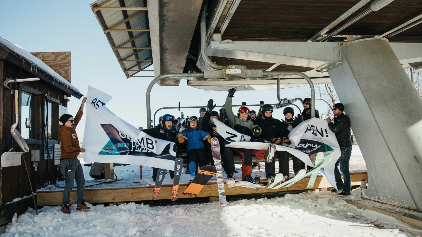 Skiers celebrating under a snowy ski lift, bright winter day.