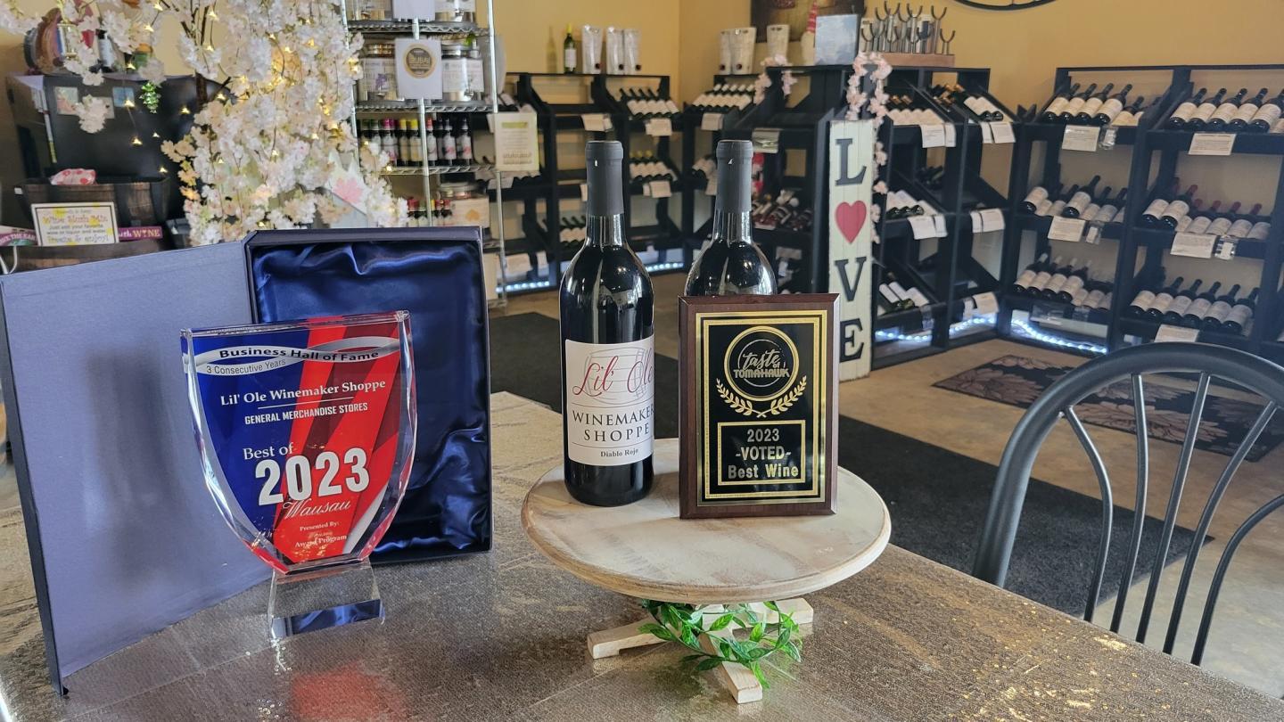 Wine bottles and awards on a table in a cozy wine shop.