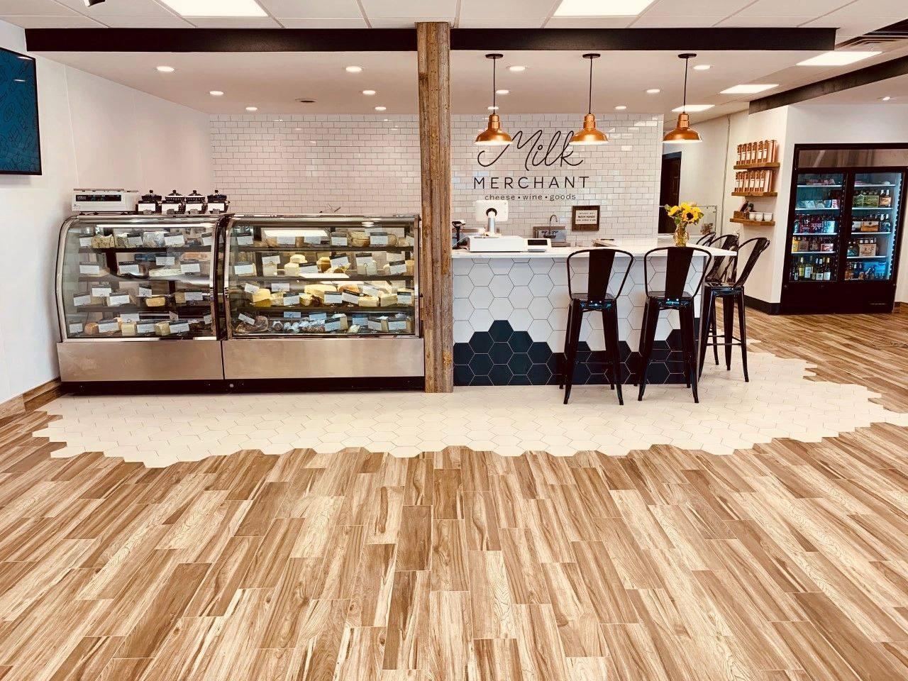 Modern bakery with wooden floors, pastry display, and bar stools.