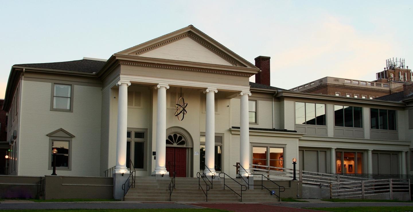 Historic building with white columns and a red door at sunset.