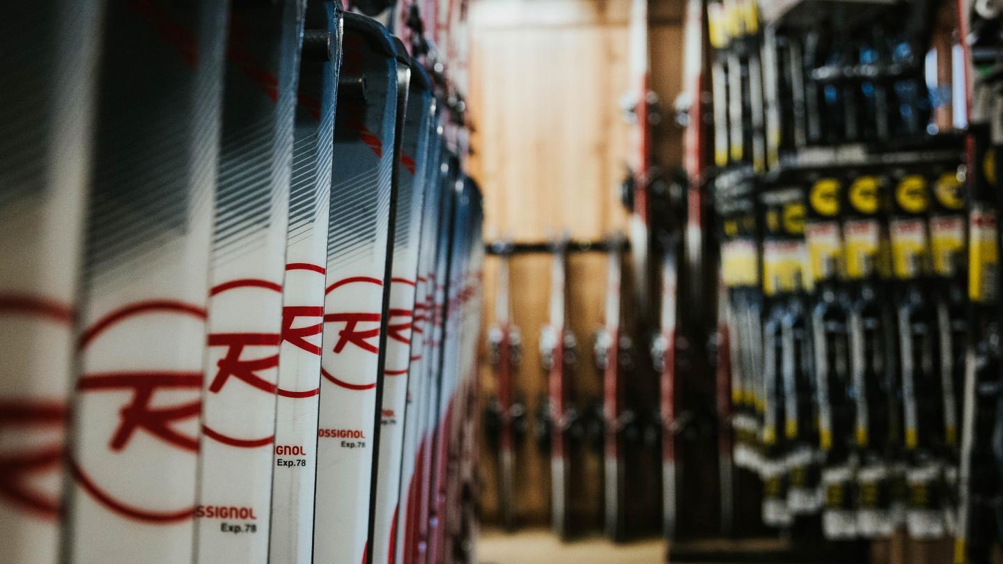Row of skis in a store aisle, close-up view, with racks on both sides.