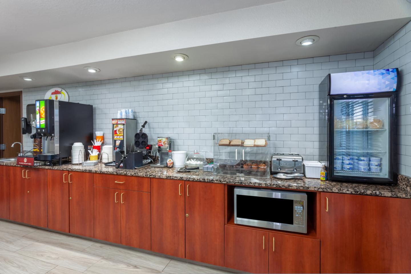 Hotel breakfast area with coffee machines, microwave, and fridge.