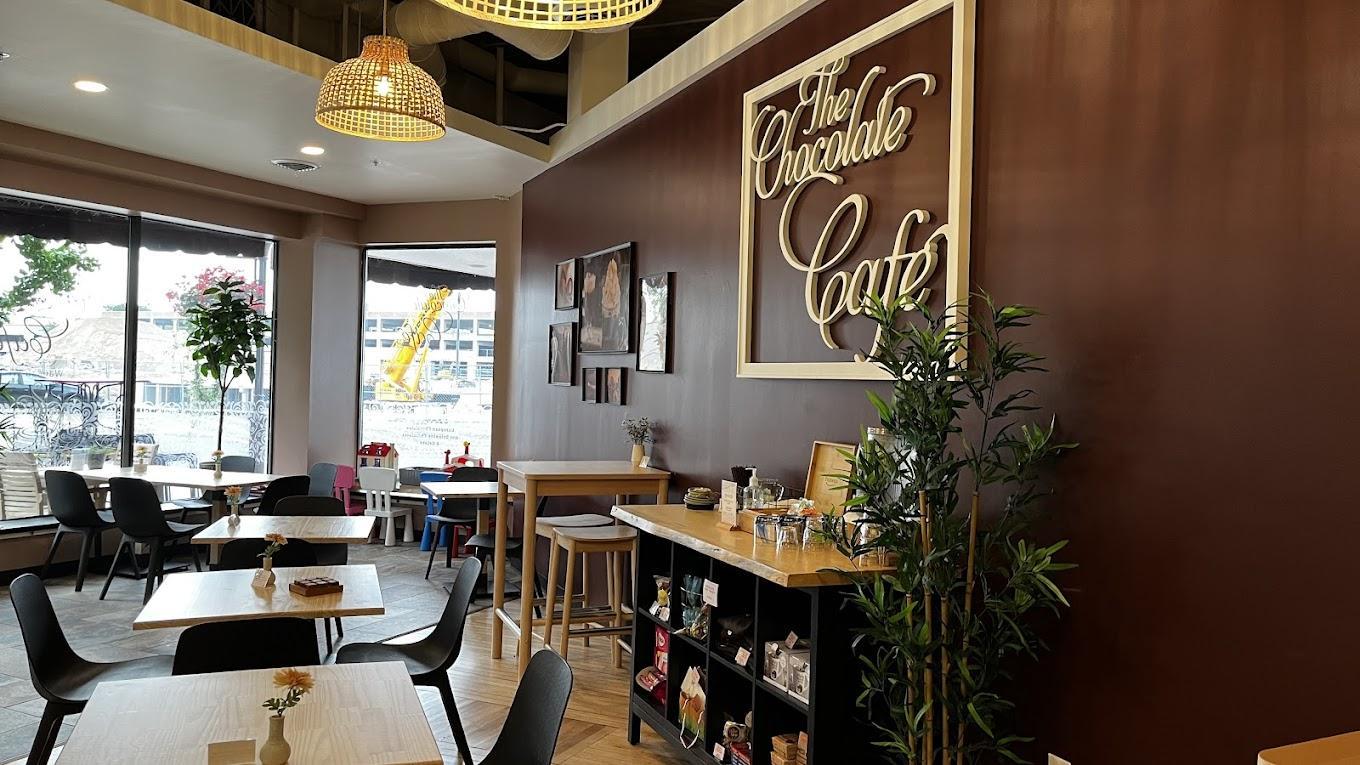 Small café interior with tables, chairs, and a brown accent wall with framed art.