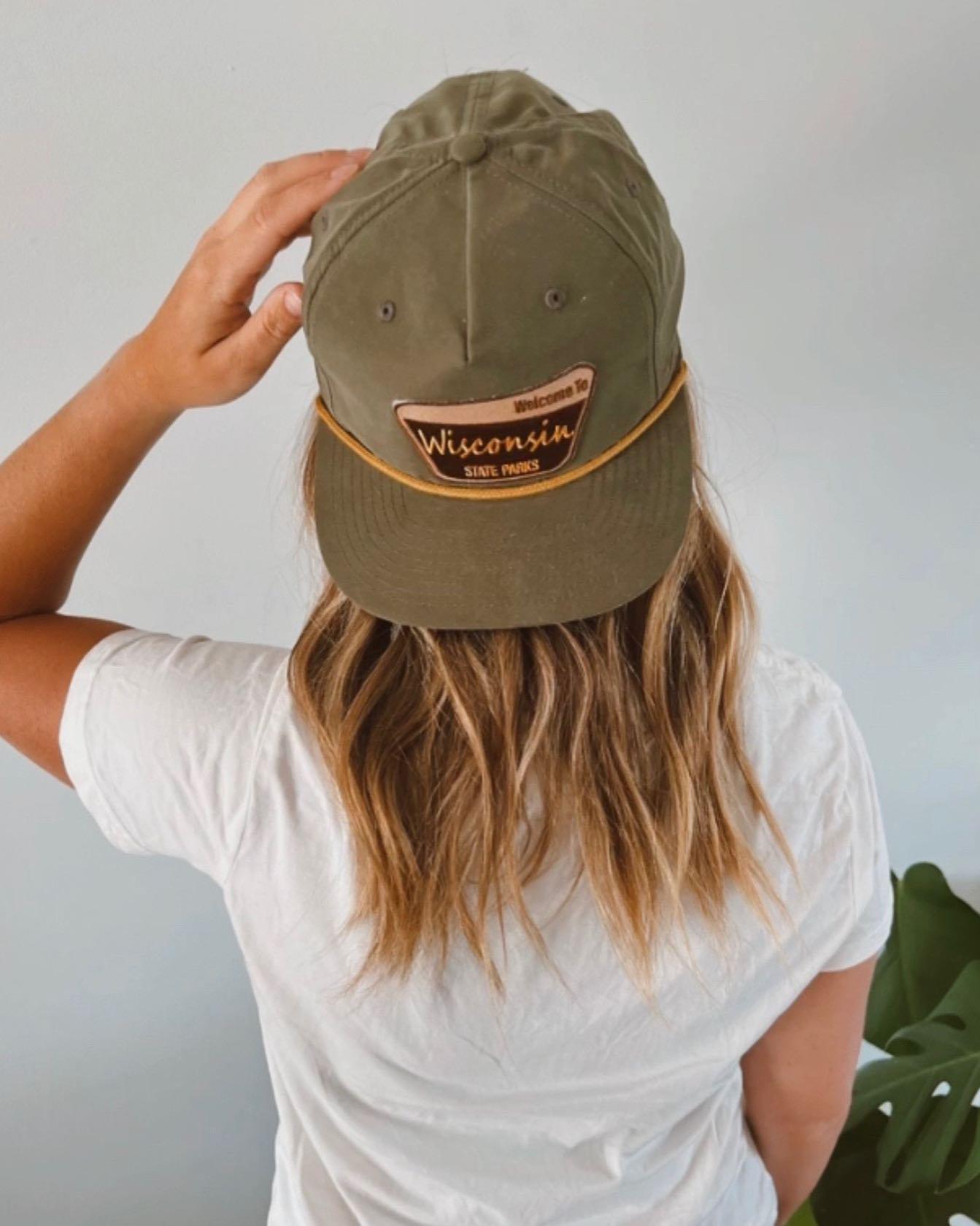 Back view of someone in a white shirt wearing an olive green cap with a patch.