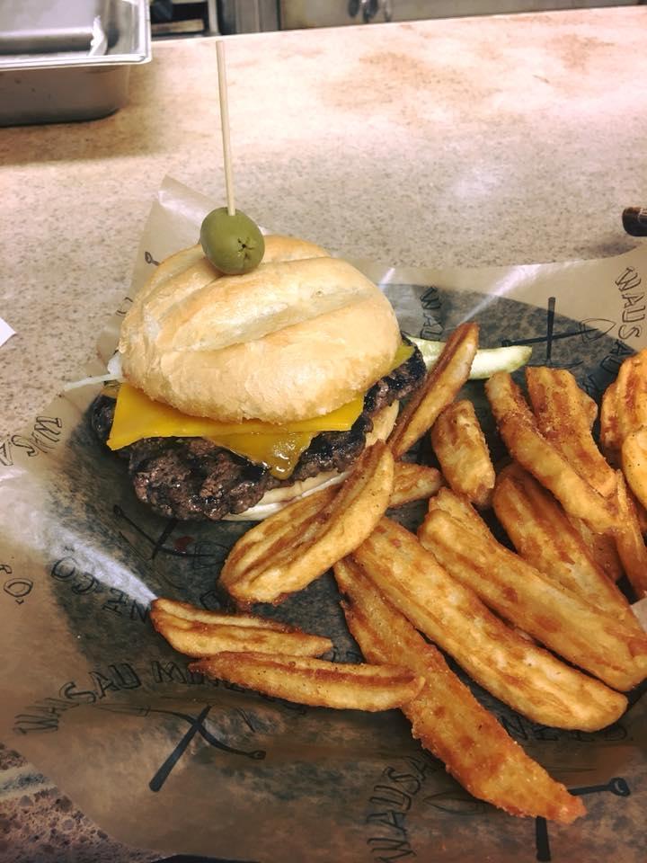Burger with cheese and olive, served with crinkle-cut fries on the side.
