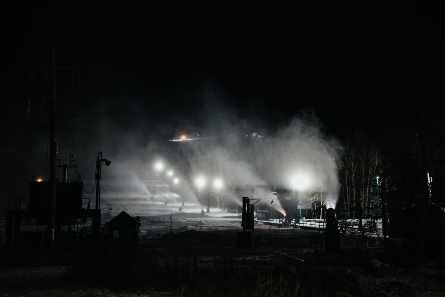 Night scene of industrial area with bright lights and steam.