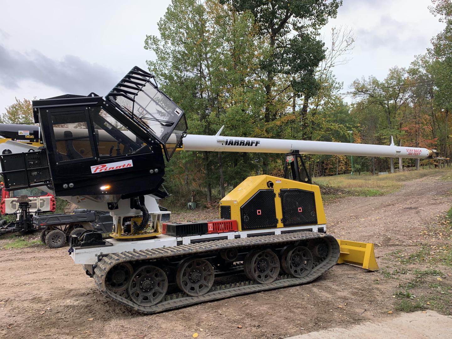 Tracked vehicle with long crane in a wooded area.