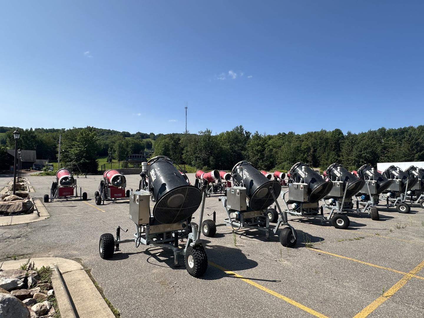 Outdoor equipment lined up in a parking lot under a clear blue sky.