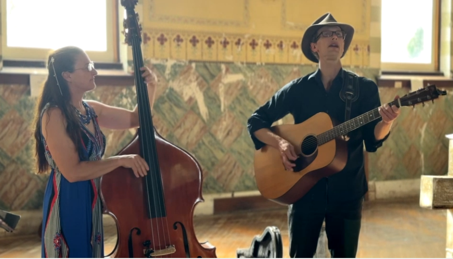 Musicians playing guitar and double bass indoors, in a well-lit room.