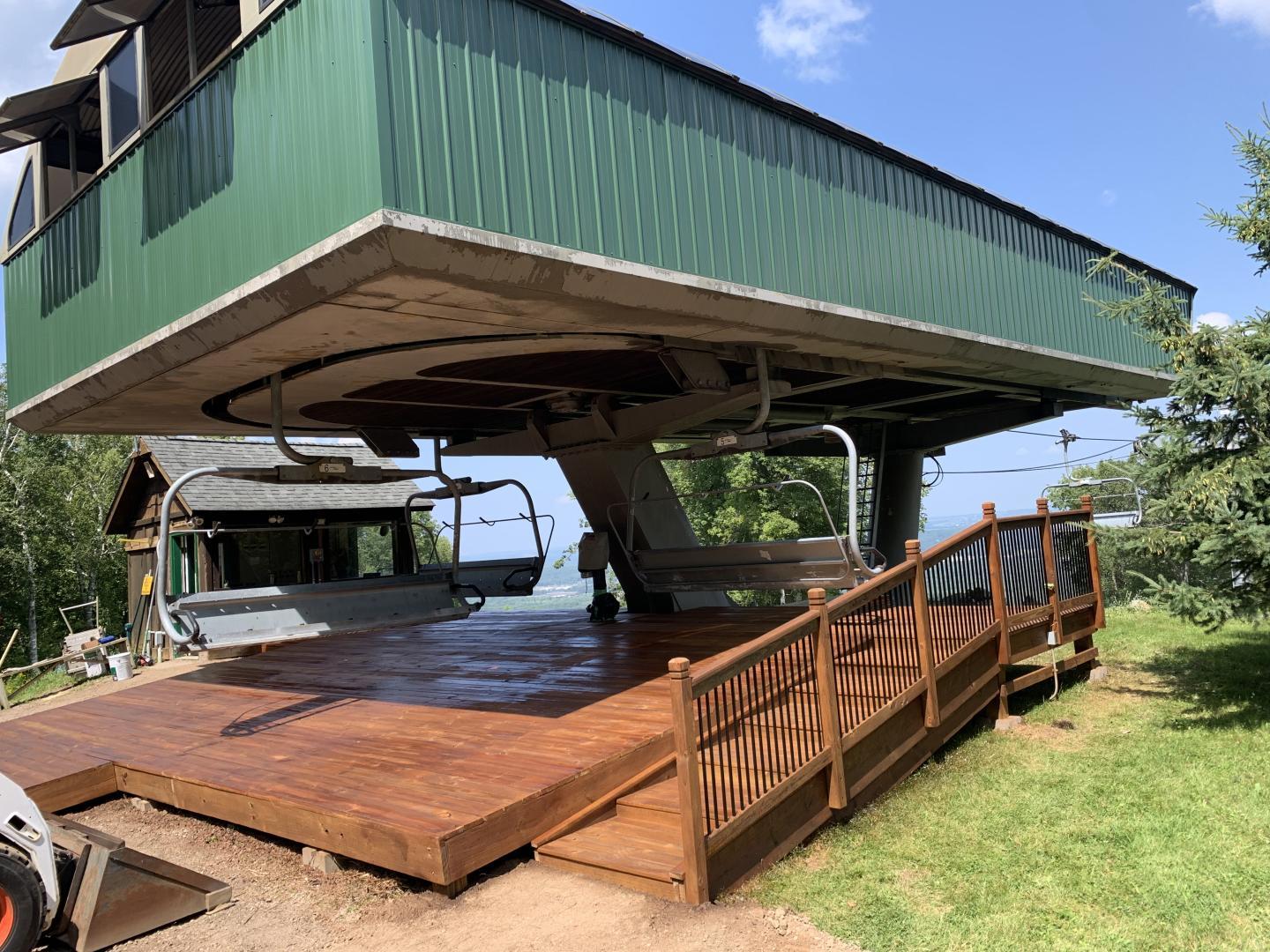 Chairlift station with wooden platform under a blue sky.