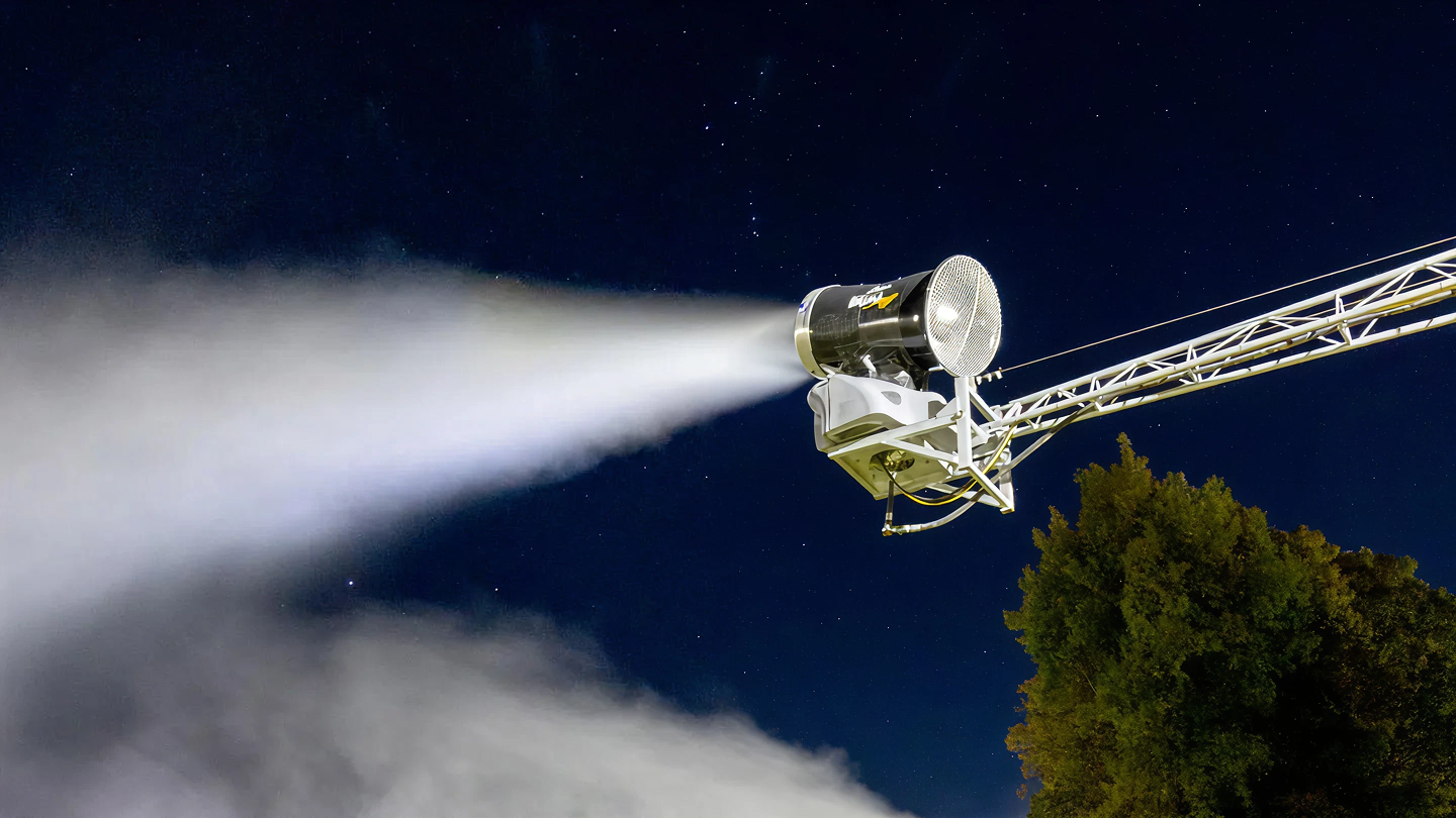 Snowmaking machine shooting mist into the night sky.