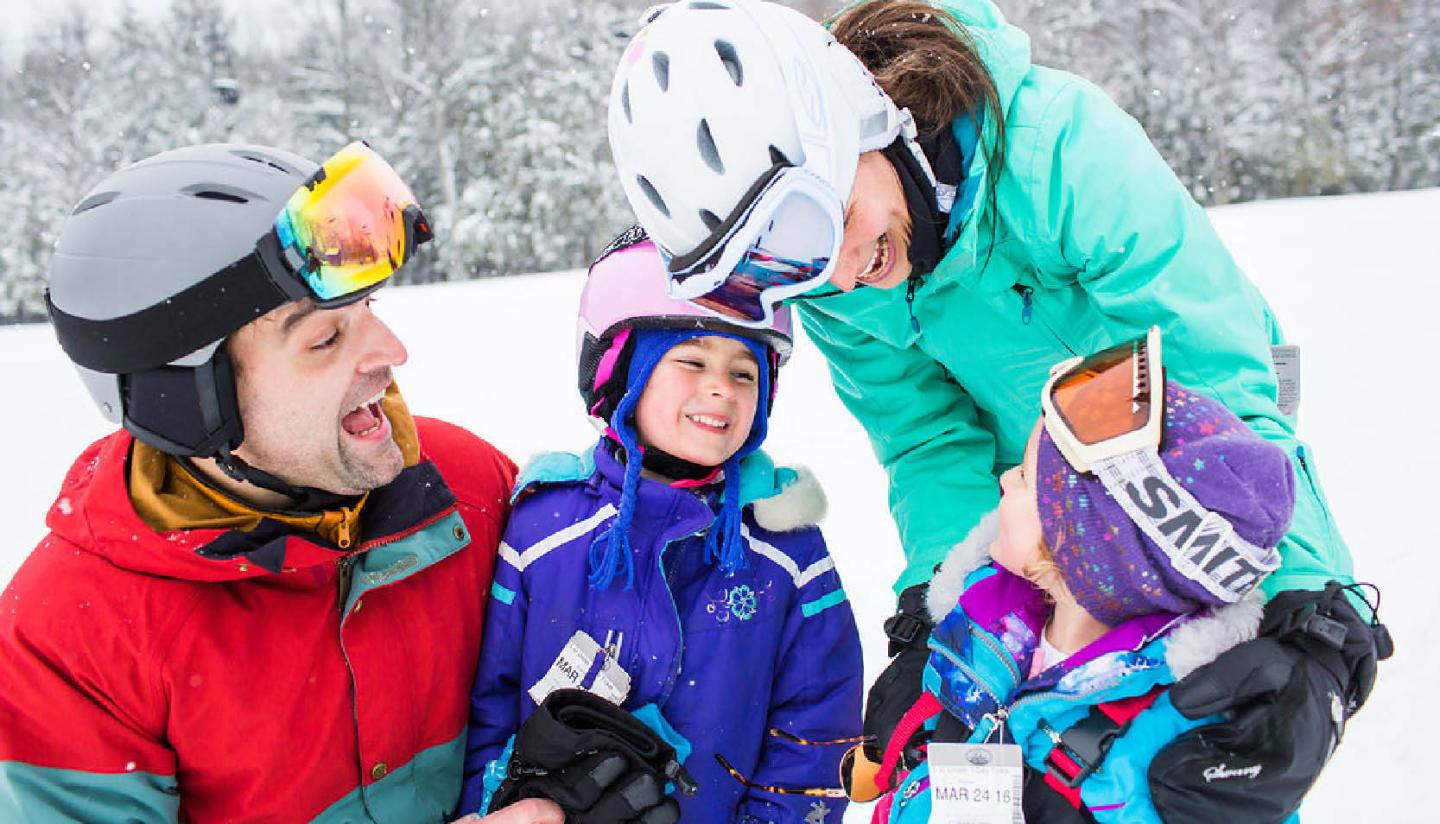 Family smiling while skiing in snowy landscape.
