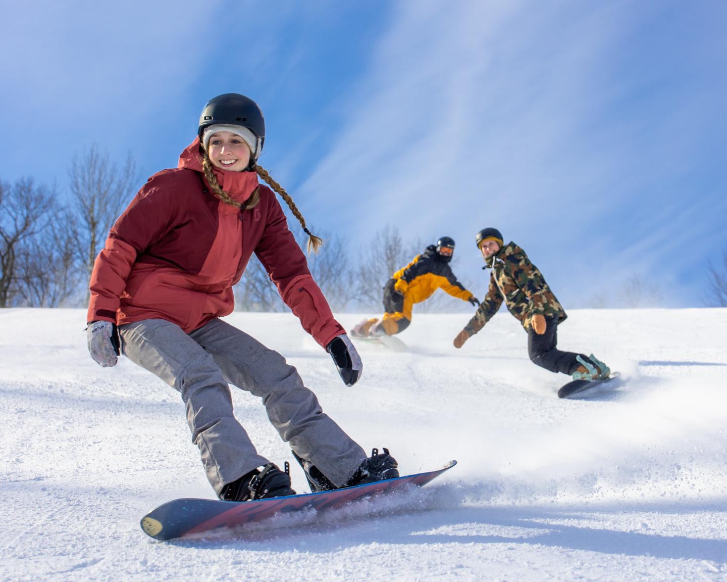 Snowboarders enjoying a downhill ride on a sunny day.