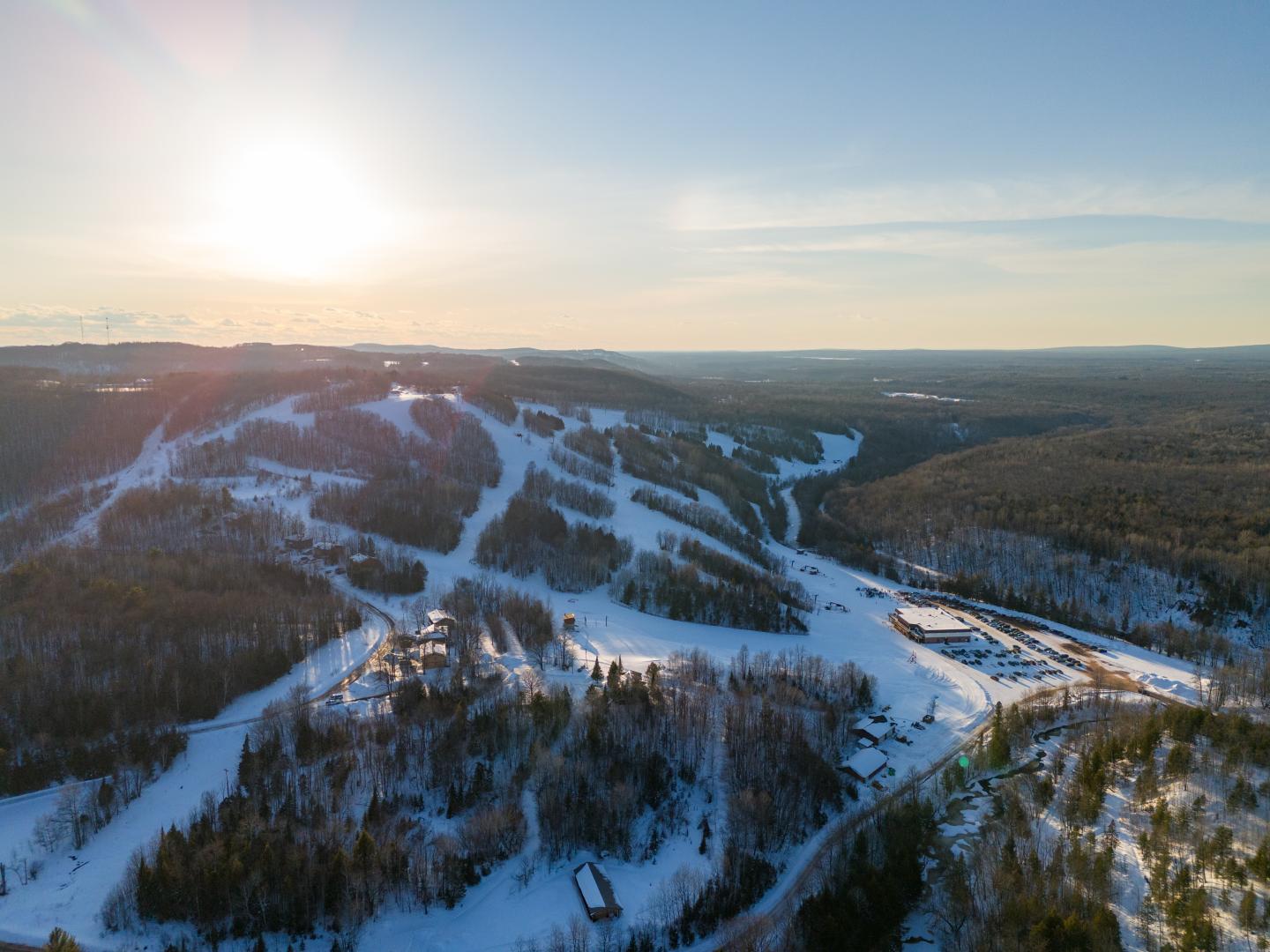 Snowy ski slopes under a clear sky at sunrise.