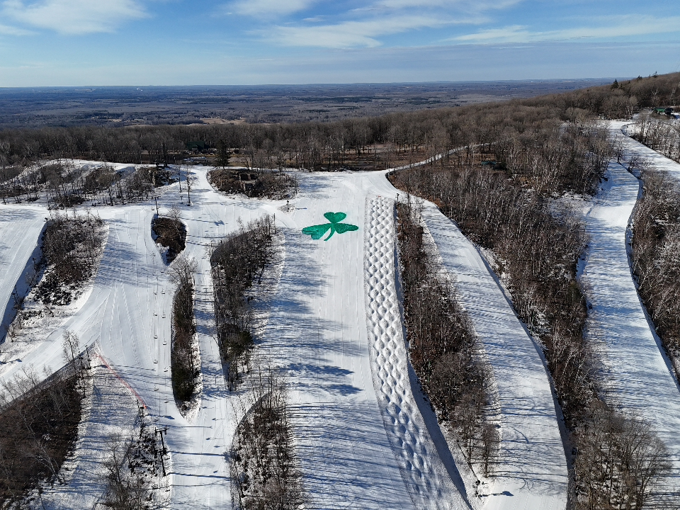 Snowy ski slopes with a large green shamrock design.
