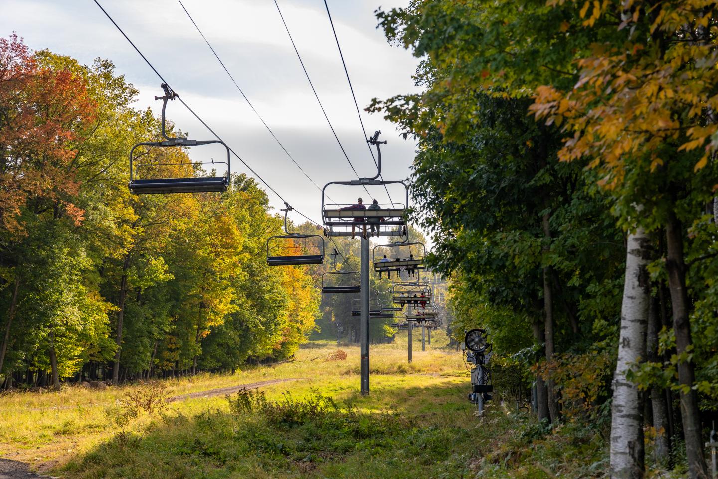 Ski lift in autumn forest with colorful leaves.
