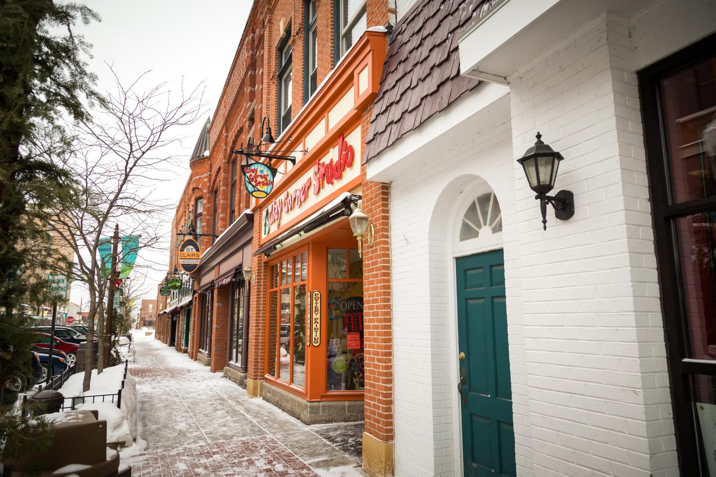 Snowy street lined with brick buildings and shops.